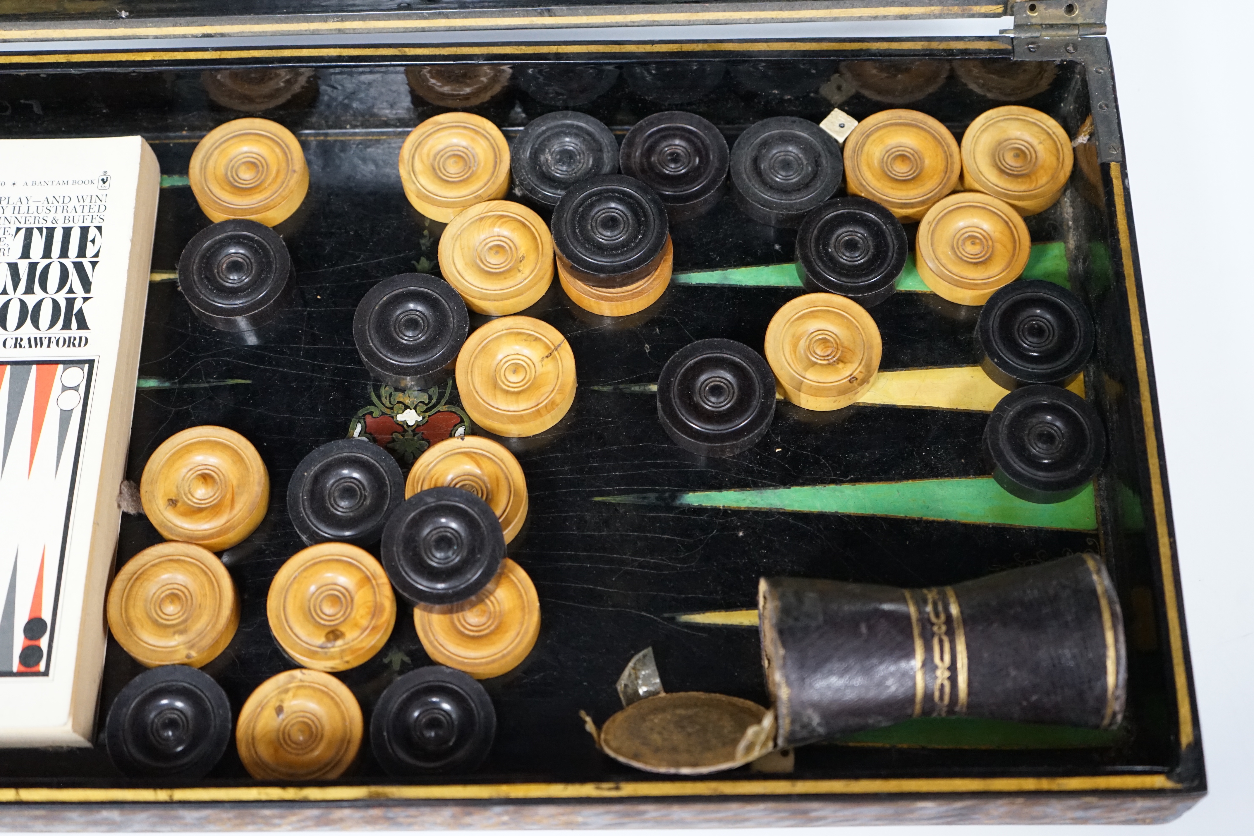 A 19th century papier maché folding games board for chess and backgammon, containing a wooden draughts set etc. with gilt decoration, 41 x 45cm unfolded